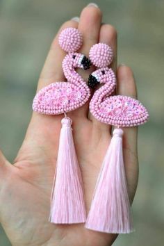 a hand holding two pink flamingos with tassels