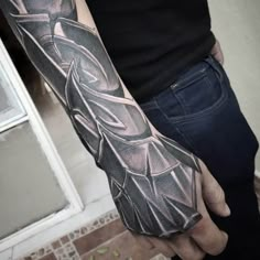 a man's arm with a black and grey tattoo design on the left arm