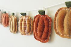 a row of felt pumpkins hanging from a line on a wall next to a white wall