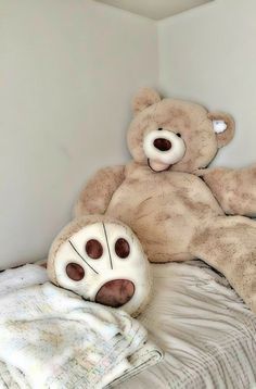 a teddy bear laying on top of a bed next to a white pillow and blanket