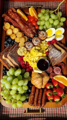 a platter filled with lots of different types of food and fruit on top of a checkered table cloth