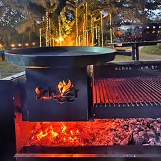 an outdoor bbq grill is lit up at night with lights on the trees in the background