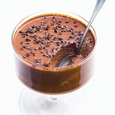 a chocolate dessert in a glass bowl with a spoon sticking out of the top and sprinkled with chocolate chips