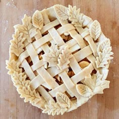 an apple pie on a wooden table with leaves