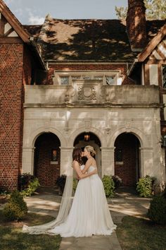 a bride and groom standing in front of a large brick building