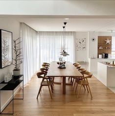 a dining room table and chairs in front of a large window with sheered curtains