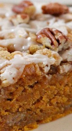 a close up of a piece of cake on a plate with icing and nuts