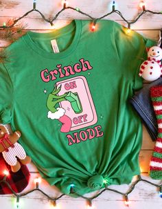 MODE SWITCH SHIRT - "Grinch Mode On" Tee Get ready to activate your Grinch mode with this playful "Grinch Mode On" shirt! Perfect for adding a bit of humor to your Christmas celebrations, this tee makes a great gift for family or friends who embrace the Grinchmas spirit with a grin. Product Features: Material: Crafted from 100% cotton for a comfy and classic fit. Sport Grey is 90% cotton, 10% polyester; Ash Grey is 99% cotton, 1% polyester; Heather colors are a blend of 50% cotton and 50% polyester. Fabric Weight: 5.0-5.3 oz/yd² (170-180 g/m²) for a solid yet lightweight feel. Fit: The unisex classic tee is designed to provide a structured look, ideal for both casual and layered streetwear styles. Construction: Features open-end yarn, tubular fabric, taped neck and shoulders, and double se Grinch Mode On, Family Grinch Shirts, Festive Green Casual Tops, Grinch Family Shirts, Funny Green Tops As A Gift, Casual Green Holiday Shirt, Casual Green Shirt For Holiday, Casual Green Christmas Shirt, Green Cotton Christmas Shirt