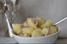 a white bowl filled with potatoes and onions