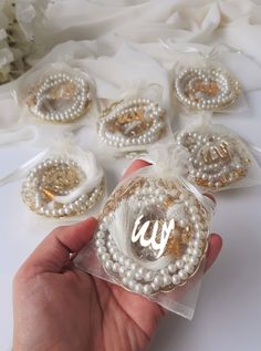 a person holding some pearls and brooches in front of white fabric with flowers