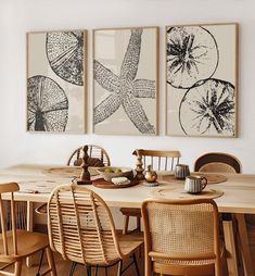 a dining room table with four chairs and two pictures on the wall above it,