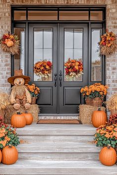 two scarecrows with pumpkins and hay bales in front of a door