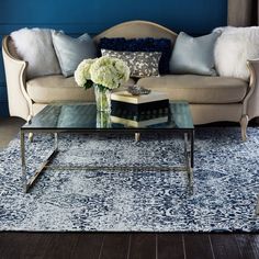 a living room with a couch, coffee table and pillows on top of the rug