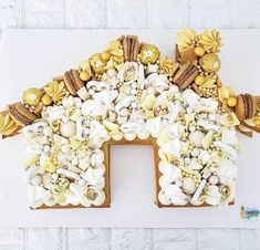 a house made out of cookies with flowers and shells on it's sides, sitting on a white surface