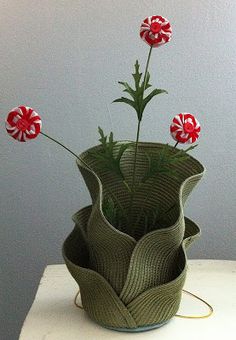 three red flowers in a green vase on a white table