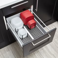 two red and one white dishes are in the pull out drawer on the kitchen cabinets