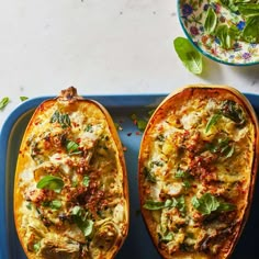 two stuffed squash halves with spinach and cheese on a blue tray next to a bowl of salad