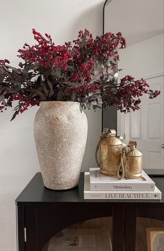 a vase filled with red flowers sitting on top of a table next to a mirror