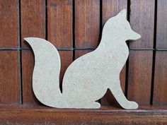 a wooden cutout of a fox sitting on a shelf next to wood slats