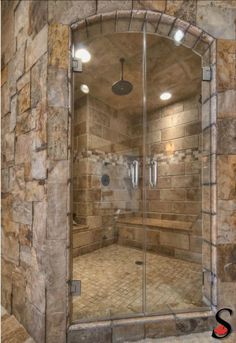 a walk in shower sitting inside of a bathroom next to a stone tiled wall and floor