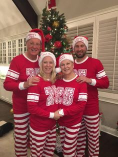 three people in matching red and white pajamas posing for a photo with a christmas tree behind them