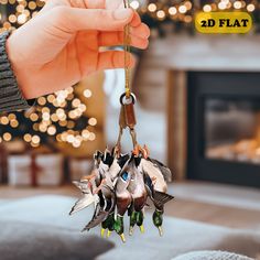 a hand holding a keychain with several birds hanging from it's end