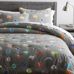 the comforter is made up with many different nfl logos on it, including football helmets