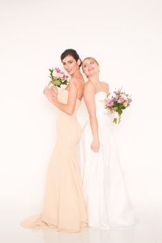 two beautiful women standing next to each other holding bouquets in their hands and posing for the camera