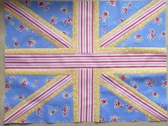 a blue and yellow quilt with pink flowers on the front, white polka dot dots