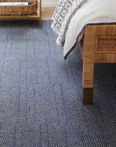 a bedroom with blue carpet and bedding in the corner, next to a wicker chair