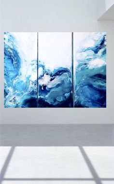 three abstract paintings are displayed in an empty room