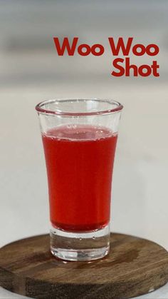 a shot glass filled with red liquid on top of a wooden coaster that says woo woo shot