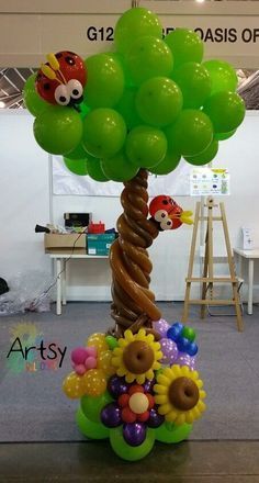 a balloon tree with lots of balloons attached to it's trunk and flowers on top