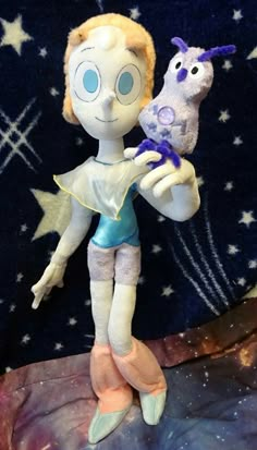 a doll holding a stuffed animal on top of a purple and blue surface with stars