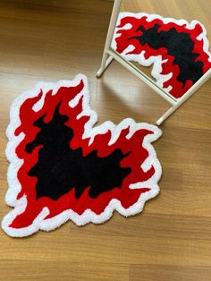 a red and black rug sitting on top of a wooden floor next to a chair