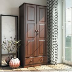 a tall wooden armoire sitting next to a window