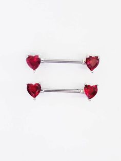 two red heart shaped piercings with silver posts on a white background, one is in the shape of three hearts