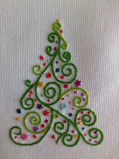 a hand embroidered christmas tree on a white fabric with multicolored stars and swirls