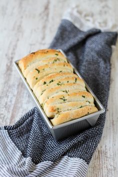 a loaf of bread sitting on top of a blue and white towel next to a metal pan