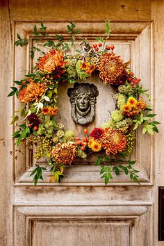 a wreath on the front door of a house decorated with flowers and leaves is displayed