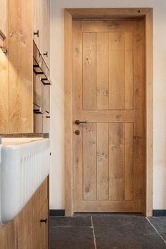 a wooden door in a kitchen next to a white sink and counter top with drawers