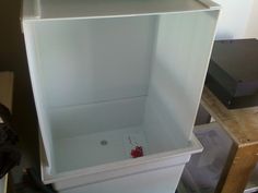 an empty white cabinet sitting on top of a hard wood floor next to a wall