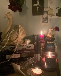 two candles are lit on a table with books and other items in front of them