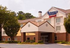 the front entrance to a hotel with trees and bushes around it, in an empty parking lot