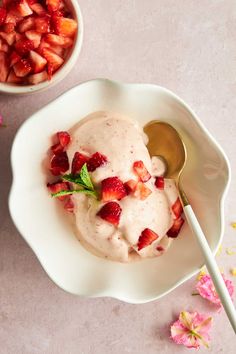 a bowl filled with ice cream and strawberries next to another bowl full of sliced strawberries