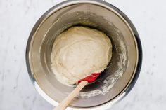 a wooden spoon in a metal bowl filled with batter on top of a white counter