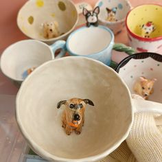 there is a bowl with a dog in it and many other bowls around it on the table