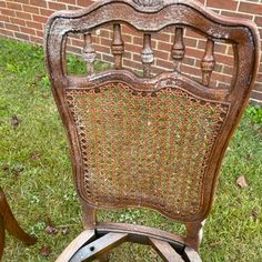 an old chair sitting in the grass next to a brick wall