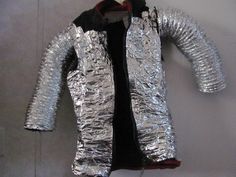 a shiny silver jacket is hanging on the wall next to a black t - shirt