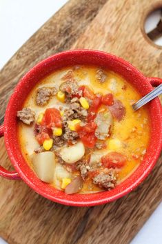 a red bowl filled with soup on top of a wooden cutting board